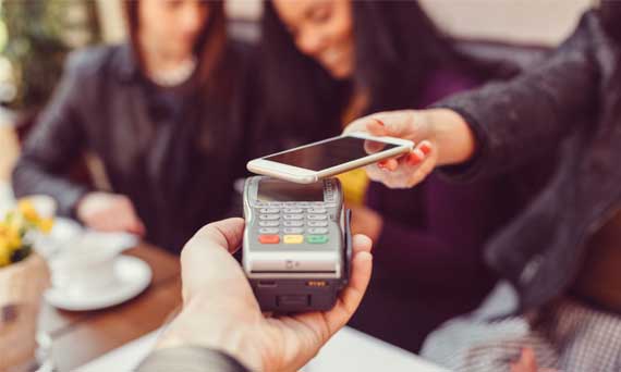 waiter hands payment processor to customer, who is paying with Apple Pay