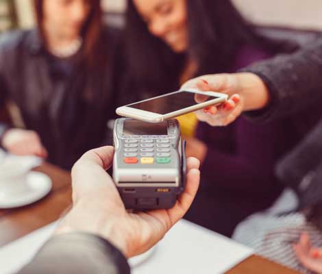 waiter hands payment processor to customer, who is paying with Apple Pay