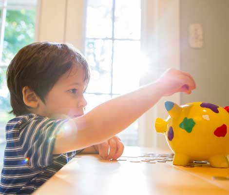 child puts coins in a piggy bank