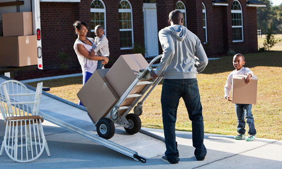 family unpacks a moving truck outside of their new home