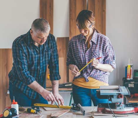 two carpenters work on a project in their shop