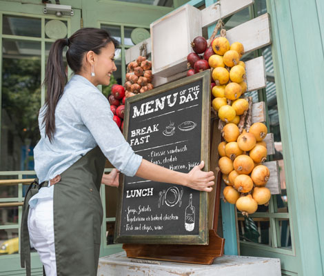 business owner places sign with a daily menu outside of restaurant